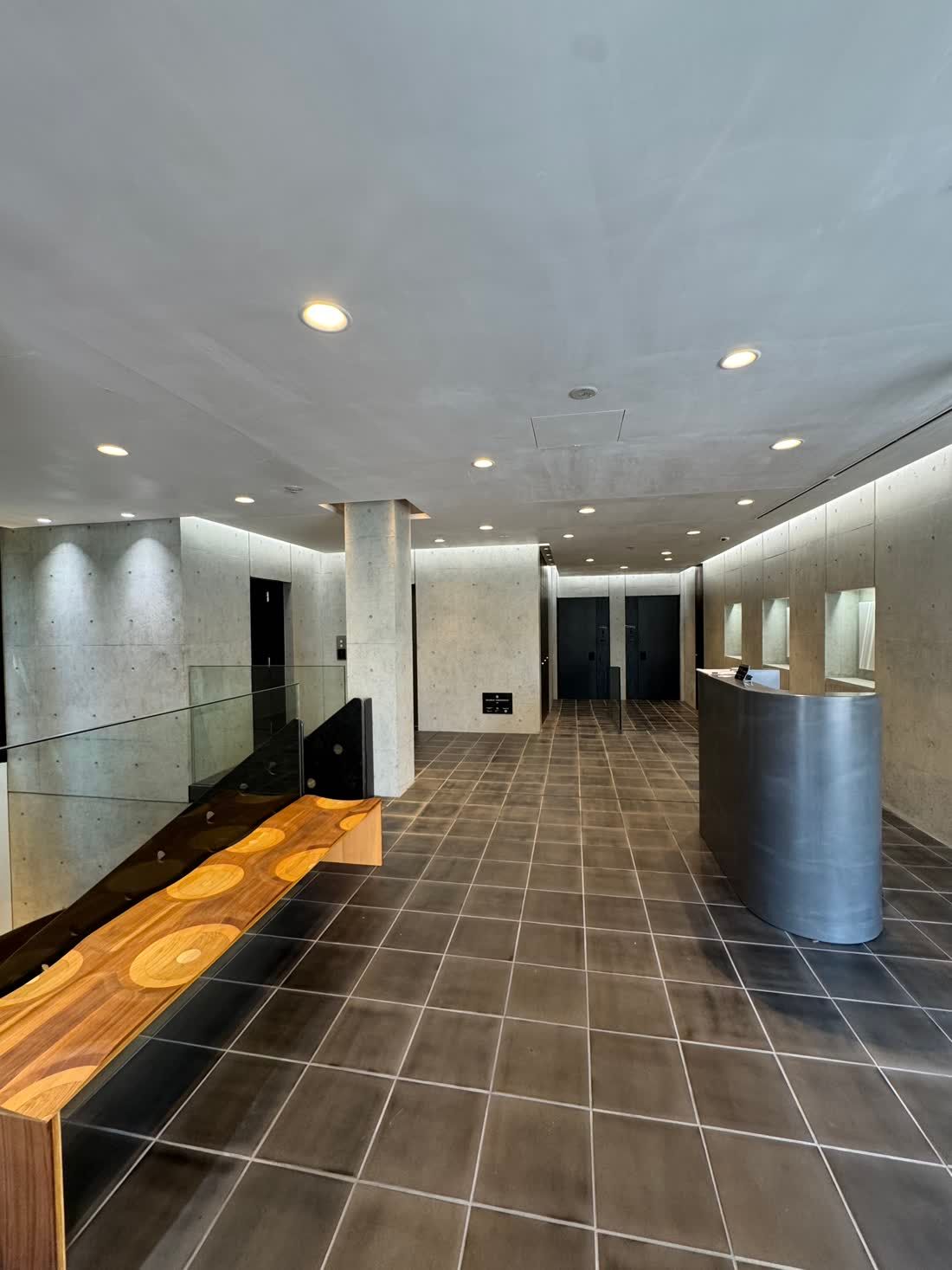 The lobby: warm timber and concrete, quietly lit.